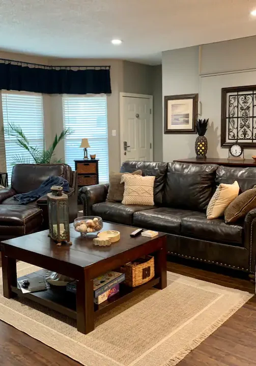 A living room with leather furniture and wood floors.